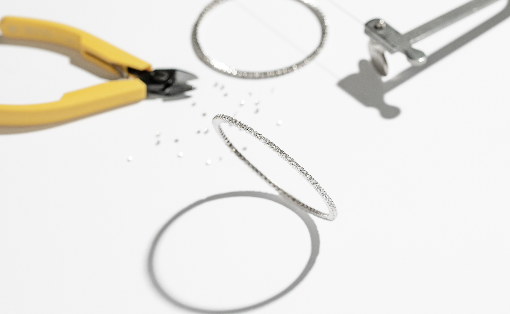 ILA SODHANI's Lisa Bangles being assembled; shown on a white background with loose diamonds, wire cutters, and gauge tool.