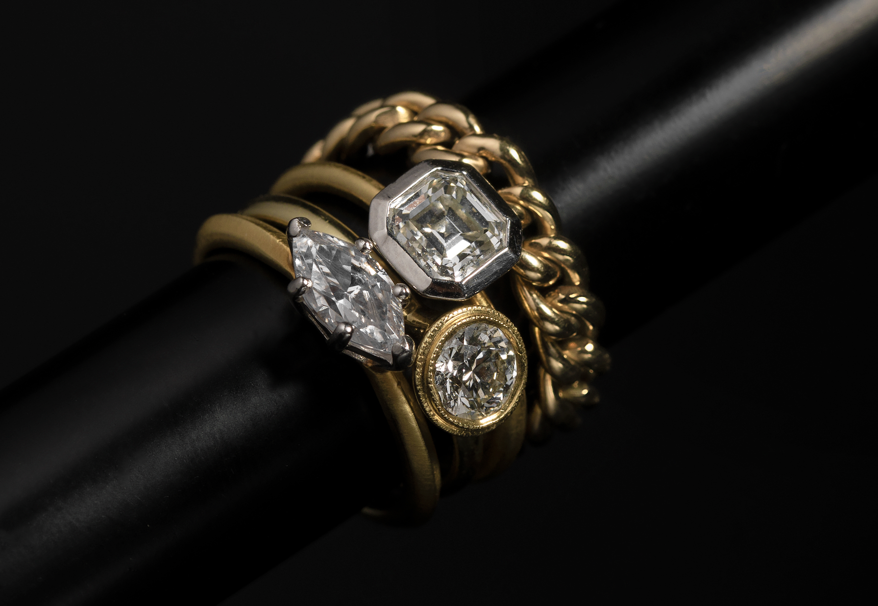 ILA SODHANI's nesting rings in yellow gold, stacked with the Link Ring on top; shown on a black pole.