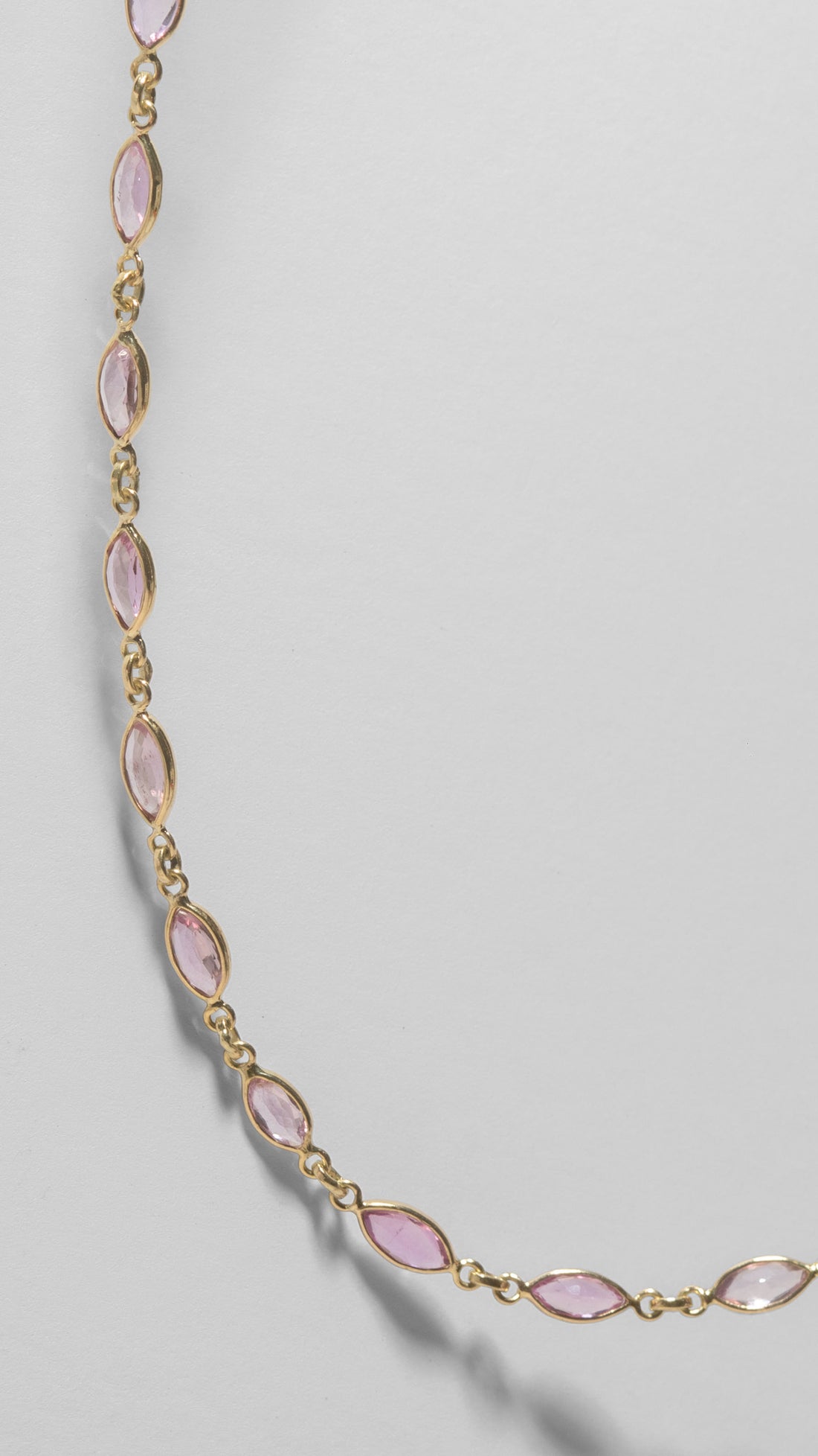 ILA SODHANI Camellia Necklace shown in a close shot of the marquise cut natural pink sapphires set in yellow gold on a white background.