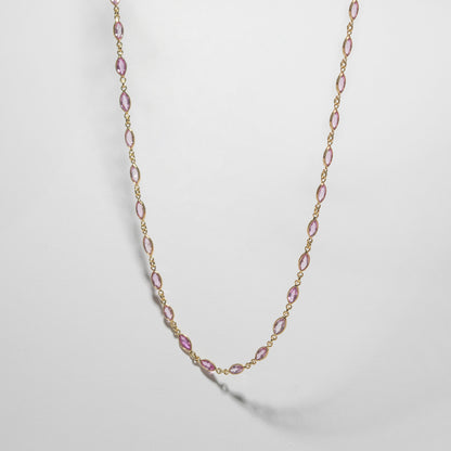 ILA SODHANI Camellia Necklace with marquise cut natural pink sapphires set in yellow gold; shown hanging in front of a white background.