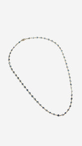 ILA SODHANI Capri necklace shown clasped and laid flat on a white background; natural blue sapphires set with yellow gold chain.