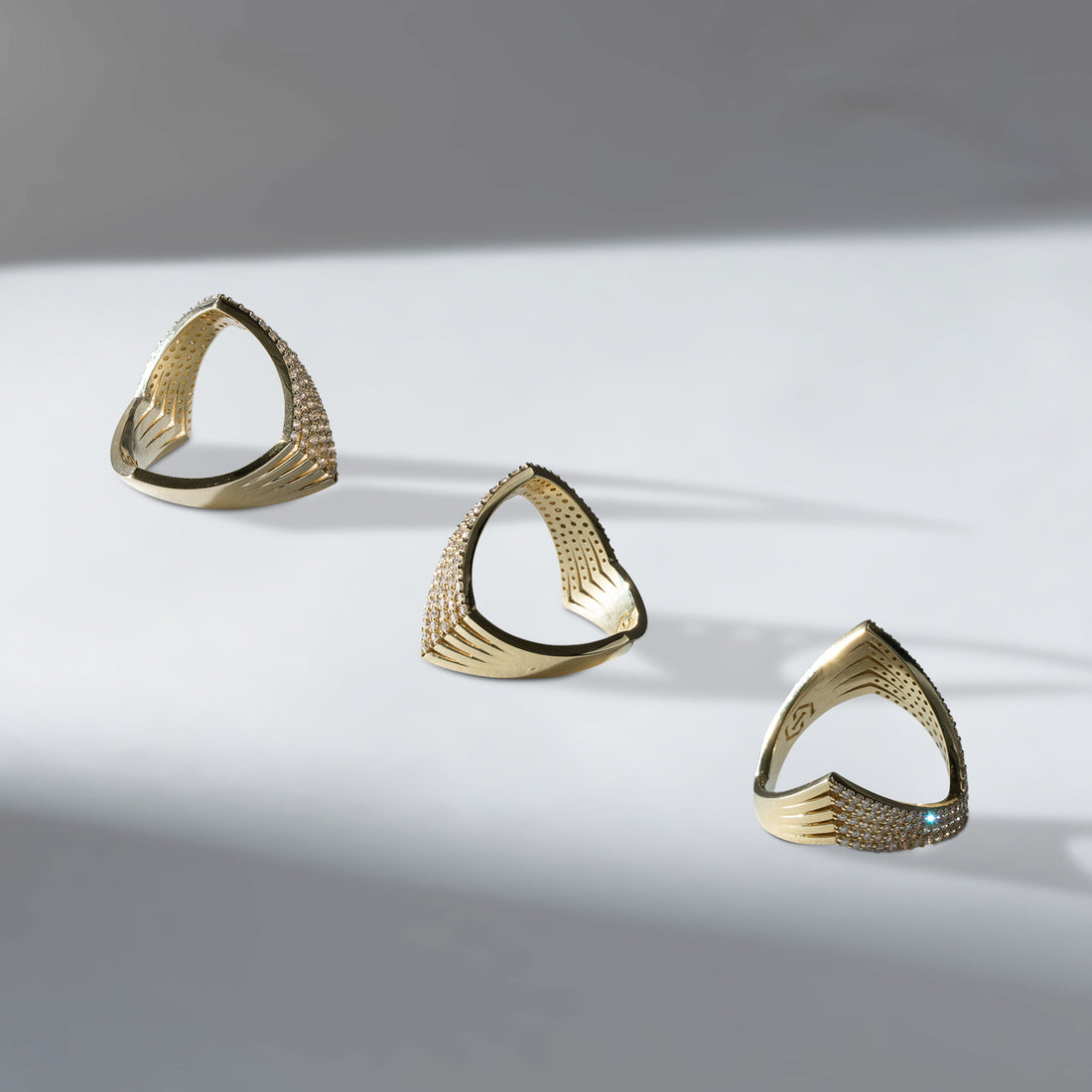 Three ILA SODHANI Never Have I Ever Rings in yellow gold with natural diamonds facing different directions to show sides of the interior; shown on white background.